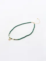 Collar corto de cuentas facetadas color verde esmeralda y detalles dorados. Dije de luna creciente con incrustaciones de strass. Cierre de mosquetón.