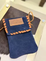 Funda para celular de gamuza azul marino con correa de cuero marrón y aplique de cuero marrón con logo de la marca.