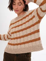 Sweater de punto color beige con rayas horizontales color marrón, de corte holgado y largo hasta la cintura.