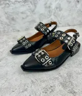 Ballerinas negras de cuero con punta cuadrada, tira sobre el empeine con hebilla metálica y detalle de ojalillos plateados.