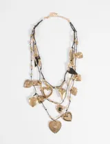 Collar de múltiples hilos de cordón negro con una variedad de dijes en forma de corazón de color dorado. Los dijes presentan distintos tamaños y texturas, incluyendo diseños lisos, calados y con relieves, acompañados de pequeñas cuentas metálicas doradas distribuidas a lo largo de los hilos.