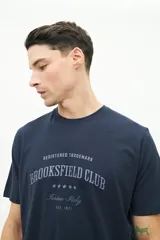 Remera azul marino de manga corta con cuello redondo y estampado frontal con el texto "Registered Trademark Brookfield Club Torino-Italy Est. 1971" en color gris.