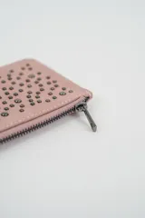 Billetera pequeña color gris claro con cierre de cremallera perimetral y tachas metálicas oscuras distribuidas en el frente.