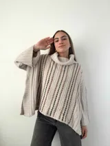 Sweater color crema de mohair con cuello alto y mangas anchas. Tejido con calados verticales y bordado a mano con lana merino.