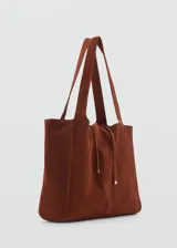 Bolso tipo shopper de gamuza color marrón, con doble asa corta y asa larga para el hombro. Tiene cierre de lazo y forro interior de algodón con un bolsillo con cremallera.