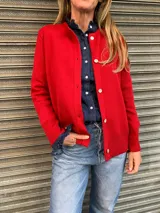 Cárdigan rojo de punto con cuello redondo y cierre frontal con botones blancos.