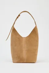 Bolso tipo saca de cuero color marrón claro, con asa de hombro ajustable y cierre imantado. Incluye cartera interior con cierre de cremallera metálica.
