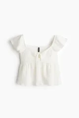 Top corto blanco de punto arrugado con escote corazón, manga circular, sección cut-out y cordón para ajustar en el busto. Modelo ajustado sobre el busto con copas preformadas fruncidas y peplum con leve vuelo.