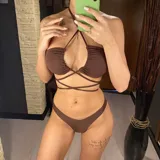 Conjunto de bikini color marrón, compuesto por un corpiño bandeau con tiras finas que se cruzan en el frente y una falda pareo elastizada.