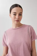 Remera rosa pastel de manga corta con tachas plateadas en los hombros.