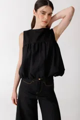 Top musculosa de lino color rojo, con cuello redondo y diseño estilo balloon con volumen en el ruedo. Cuenta con cierre de botones en la parte trasera.