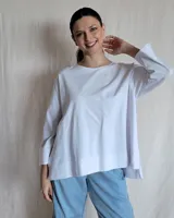 Remerón blanco de corte amplio, con cuello redondo y mangas largas con puños abullonados.