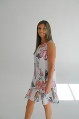 Vestido corto sin mangas, con estampado de flores rosas y naranjas sobre fondo blanco.