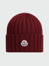 Gorro de lana tejido a punto acanalado, color bordó, con parche circular del logo de Moncler en el frente.