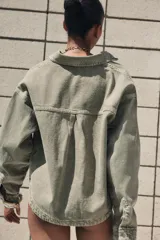 Cazadora de denim verde oliva, con cuello solapa, manga larga, bolsillos delanteros de plastrón y cierre frontal con botones metálicos.