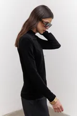 Polera negra de terciopelo con cuello alto y mangas largas.