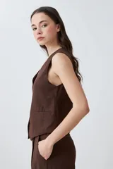 Chaleco sastrero color chocolate, de lino, con cuello en V y cierre frontal con botones.
