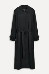 Trench negro oversize con cuello solapa, manga larga con trabilla y botón, bolsillos delanteros, cinturón ajustable con lazadas, abertura en la espalda y cierre frontal con botones ocultos por solapa.