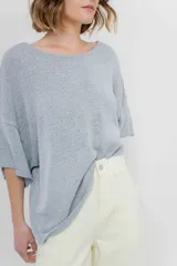 Sweater color crudo de tejido liviano con textura semi traslúcida, escote redondo y mangas amplias estilo murciélago.