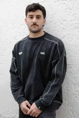 Buzo negro de frisa 100% algodón con calce oversize y lavado gastado. Presenta costuras a contratono, recortes y logos estampados en el frente y en el puño.