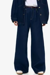 Pantalón de jean azul oscuro de tiro alto, corte recto y pierna ancha. Diseño de cinco bolsillos con costuras a la vista. Inspirado en los años 70.