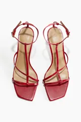 Sandalias rojas de tacón con punta cuadrada y tiras finas sobre el empeine. Pulsera ajustable con hebilla de metal.
