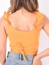 Blusa corta color naranja, con escote cruzado y volados en los hombros.