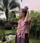 Blusa rosa de encaje con volados y cuello alto.