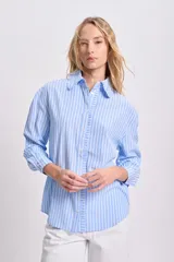 Camisa celeste a rayas verticales blancas, de manga larga con puños elásticos y volados en el frente.