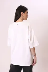 Remera negra de corte oversize con estampado abstracto en tonos rojos, grises y blancos.