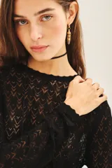 Remera negra de tejido calado con lurex, corte ajustado y mangas largas.
