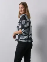 Blusa de gasa estampada con flores verdes sobre fondo blanco, de la marca Sioni. Tiene mangas cortas amplias con abertura y botón.