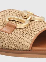 Sandalias bajas color beige con diseño tejido y detalle de hebilla dorada.