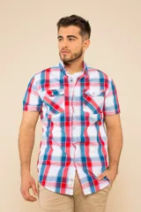 Camisa de manga corta con estampado a cuadros en tonos rojo, azul y blanco. Tiene cuello clásico, cierre con botones y dos bolsillos con solapa en el pecho.