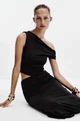 Falda midi color crema, de tiro alto con cintura elástica y detalle de pliegues laterales.