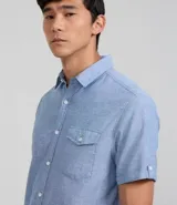 Camisa de hombre de manga corta confeccionada en una mezcla de lino y algodón, marca Marfinno. Presenta un calce confort, cuello clásico, cierre frontal con botones y un bolsillo de parche con solapa en el pecho. Las mangas cuentan con un detalle de dobladillo.