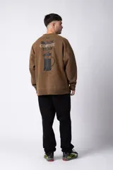 Buzo marrón de algodón rústico con lavado gastado y cuello redondo. Estampa frontal con la frase "Coffee Break". Corte oversize.