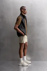 Shorts deportivos marrones de tejido técnico ligero y elástico con diferentes estructuras. Tiene forro interior, cintura elástica ajustable con cordón, bolsillos frontales, bolsillo trasero con cierre, aberturas laterales y logo estampado en la pierna.