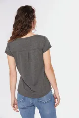 Remera color beige con escote redondo, manga corta, bolsillo en el pecho y cierre parcial con botones.