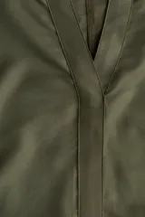 Vestido túnica a la rodilla en tejido liviano de viscosa color verde oliva con cuello mao y abertura en V. Modelo de corte holgado con hombros levemente caídos, mangas cortas y bajo recto con tajos laterales.