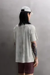 Camiseta de entrenamiento regular fit de Zara Athleticz, confeccionada en tejido técnico ligero y elástico con tecnología Quick Dry nivel 2. Presenta un estampado tipo tie-dye en tonos grises y blancos, cuello redondo, manga corta, costuras planas y termofijadas, y logo estampado en el bajo.