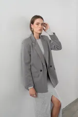 Blazer gris de corte clásico con solapas de muesca, cierre frontal con dos botones y bolsillos laterales con solapa.