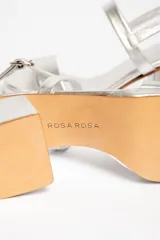 Sandalias plateadas de cuero vacuno, con dos tiras horizontales en el empeine y tobillo, ajuste con hebilla, plataforma delantera y tacón cuadrado.