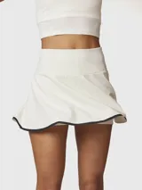 Falda skort blanca con borde negro en el dobladillo, confeccionada en tejido reciclado con tecnología Aircool. Incluye un short integrado con bolsillo.