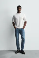 Pantalón de jean negro, corte slim fit, con tiro medio, cinco bolsillos, efecto lavado y cierre frontal con cremallera y botón.