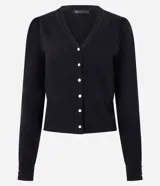 Cardigan negro de punto con cuello V y cierre frontal de botones perlados. Presenta mangas largas con detalle de botones perlados en los puños y un canesú ajustado con terminación acanalada en la cintura.