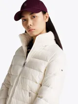 Campera Tommy Hilfiger color blanco, acolchada con plumón, de corte regular. Tiene cuello chimenea, capucha plegable, cierre de cremallera, dos bolsillos laterales con cremallera, puños elásticos con botones a presión y parche con el logo de la marca en la manga.