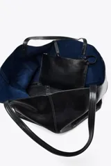 Bolso maxi shopper de cuero negro con pespuntes a tono. Tiene asas de hombro y cierre con tiras y botón. Incluye una cartera con bolsillo extraíble.