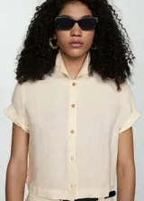 Camisa color crema de lino, con cuello camisero, manga corta con dobladillo y cierre frontal con botones.