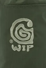 Bolsa tipo morral o porta botella de color verde oliva, con cierre de cordón ajustable en la parte superior y logo estampado en blanco en el frente. Cuenta con correas ajustables y ganchos de plástico negros para llevar cruzada o colgada.